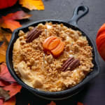 Pumpkin-shaped dessert in a black skillet with autumn leaves around it