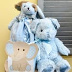 Two blue teddy bears with ribbons, one holding an elephant card