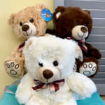 Three plush teddy bears with plaid bows, stacked together