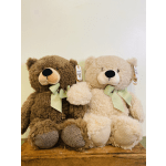 Two plush teddy bears with green ribbons sitting side by side
