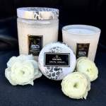 Three white candles with patterned lids and white ranunculus blooms.