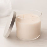 Cream-colored candle in a clear glass jar with a lid