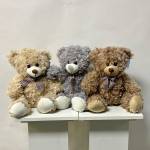 Three plush teddy bears sitting on a white shelf