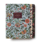 Three floral-patterned notebooks stacked on a white background