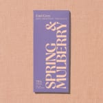 Purple Earl Grey chocolate bar package on a peach textured background