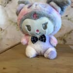 Pastel plush teddy bear with a plaid bow sitting on a wooden surface