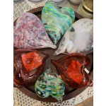Heart-shaped glass paperweights in assorted colors on a tray