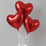 Three red heart-shaped balloons with white ribbons