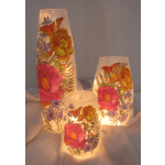 Three lit floral-patterned glass candle holders with butterflies