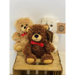 Three teddy bears with red bows on a wooden crate