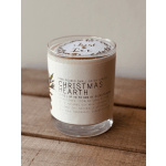 A Christmas Hearth candle in a clear glass jar on a wooden surface