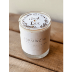White candle in a glass jar with a printed lid on a wooden surface