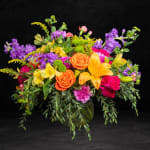Colorful mixed bouquet in a glass vase with roses and lilies