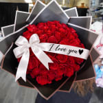 Bouquet of red roses wrapped in black paper with a white ribbon