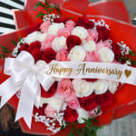 Bouquet of red, pink, and white roses with an anniversary ribbon