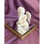 White angel figurine on a mirrored box with purple fabric background