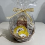 Gift basket with tea tins, tea bags, and small cups wrapped in clear cellophane