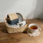 Gift basket with tea box, teacup, and saucer on a table