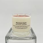 White Macintosh Apple scented glass jar candle on a clear glass block