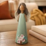 Decorative angel figurine with floral accents on a wooden table