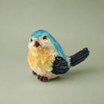 Small painted bird figurine on a plain background