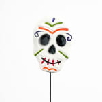 Decorative sugar skull on a stick against a white background