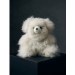 White plush teddy bear sitting on a dark pedestal