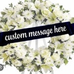 White floral wreath on an easel with a custom message ribbon