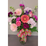 Mixed pink and purple flowers in a glass vase with a plaid ribbon