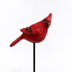 Red cardinal bird ornament on a black stake against a white background