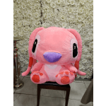 Large pink plush toy seated in front of a white floral wall.