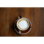 Cup of cappuccino on a saucer with a spoon on a wooden table