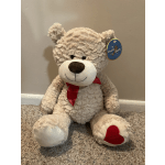 Plush teddy bear with a red ribbon and heart on one paw