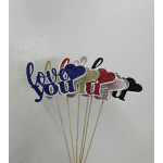 Glittery heart-shaped signs on wooden sticks against a plain wall