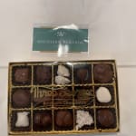 Box of assorted chocolates with a branded card on top