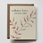 Greeting card reading "welcome home, LITTLE ONE" with leaf illustration