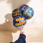 Hand holding four birthday balloons with colorful text