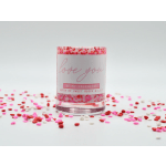 Pink candle in a glass jar with confetti around it