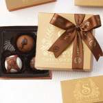 Boxed chocolates with a brown ribbon and gold packaging
