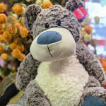 Plush teddy bear in front of an orange flower arrangement