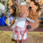 Stuffed squirrel figurine in front of a floral arrangement