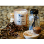 A pink candle, a glass bottle, and macarons on a tabletop with star anise