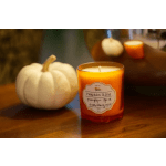 Orange pumpkin spice candle beside a white pumpkin on a table