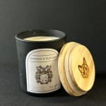 Black candle jar with a wooden lid and printed label