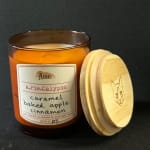 Amber candle jar with a wooden lid on a dark background
