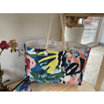 Colorful patterned tote bag with rope handles beside an orchid plant