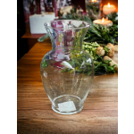 Empty clear glass vase on a wooden table with candles in the background