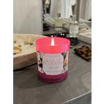 Lit pink glass candle labeled Orange Blossom on a tabletop