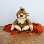 Plush lion toy sitting on a rust-colored cloth