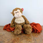 Plush monkey sitting on a red cloth backdrop